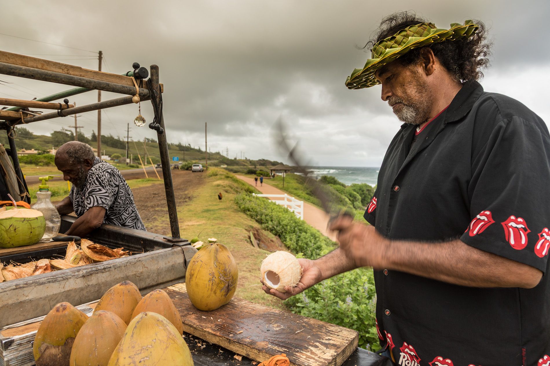 Man chopping coconut at fruit stand in Kauai, Hawaii